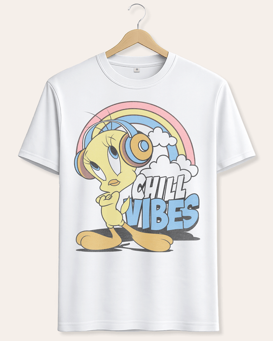 A white short-sleeve crewneck t-shirt hanging on a wooden hanger against a light beige background. The shirt features a colorful graphic of Tweety Bird wearing headphones under a pastel rainbow with the text 'CHILL VIBES'.