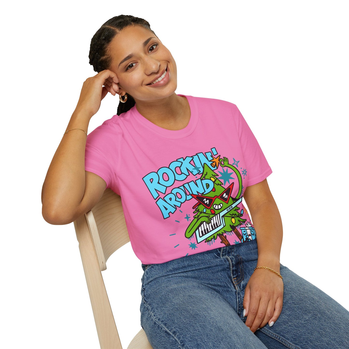 Person wearing a Retro christmas Music Inspired pink t-shirt with a colourful graphic of a Christmas tree and text Rockin Around The Christmas Tree 