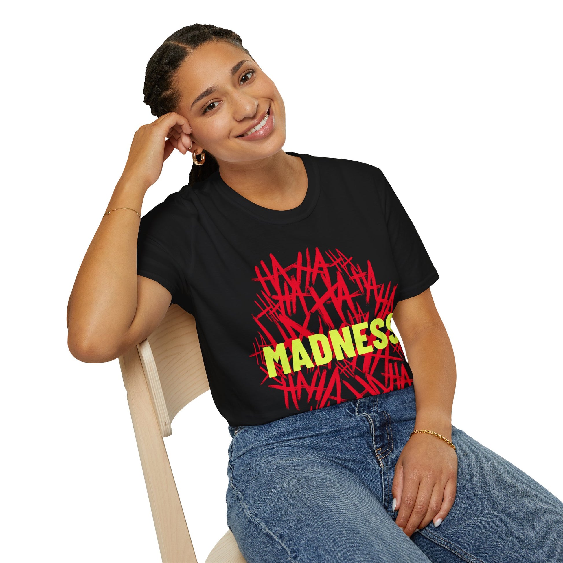 Woman wearing a black t-shirt with a Joker inspired text design, red HA HA HA HA and yellow Madness graphic text design  sitting on a chair against a white background