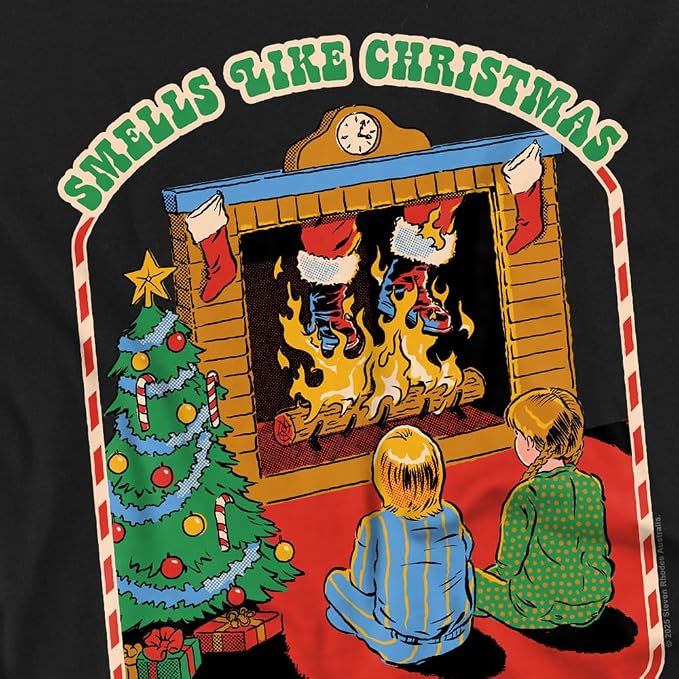 A graphic print on a black t-shirt featuring a retro Christmas scene with two children sitting in front of a burning fireplace, a decorated Christmas tree, and stockings. The text 'SMELLS LIKE CHRISTMAS' is written in green arched letters at the top.
