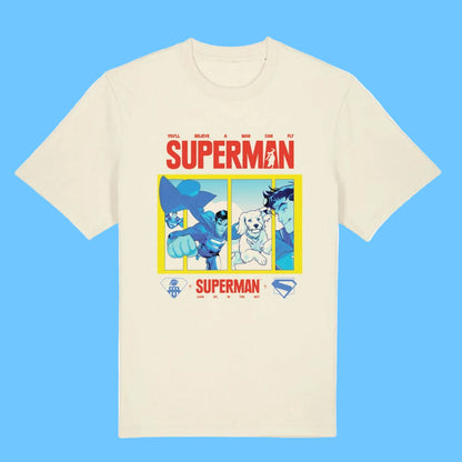 An off-white short-sleeve crewneck t-shirt featuring a colorful graphic print of Superman and other DC characters under the word 'SUPERMAN' in red, with a yellow border and small DC logos at the bottom.