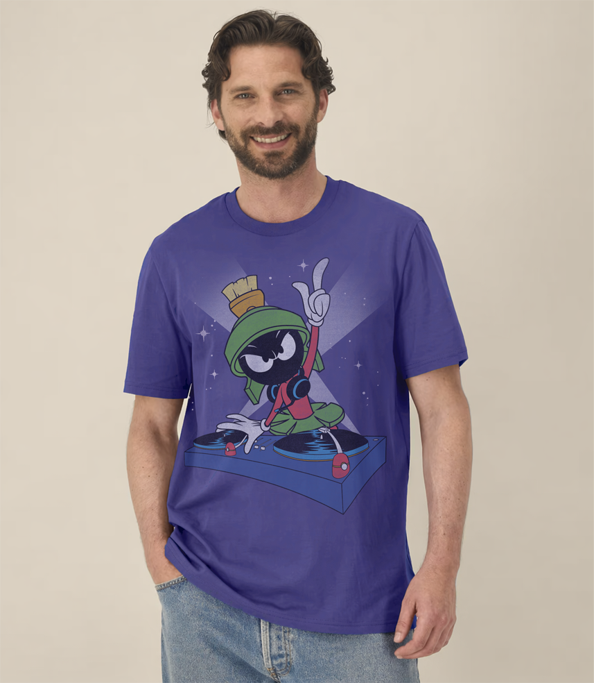 Man wearing a dusk blue short sleeve  t-shirt with graphic of Marvin The Martian  cartoon Looney Tune character  being a DJ on a beige background