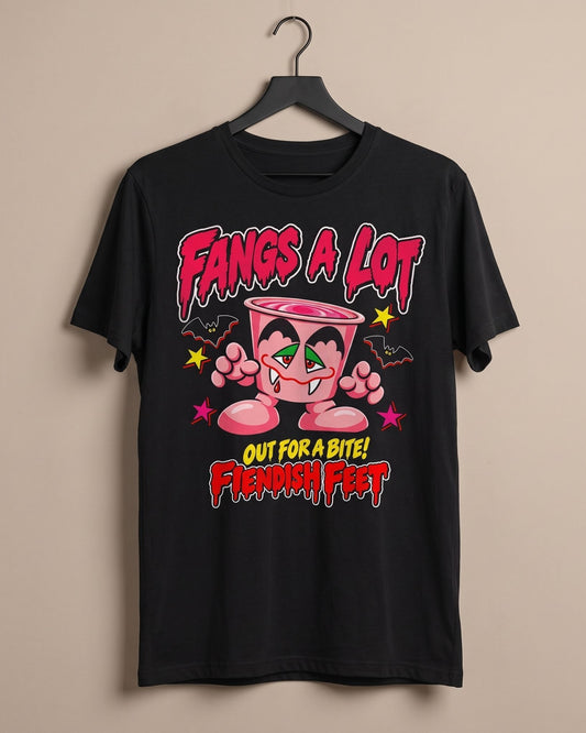 A black short-sleeve graphic t-shirt hanging on a black hanger against a solid beige wall. The shirt features a colorful cartoon graphic of a pink yoghurt pot character with green eyes and the text 'Fangs A LOT' and 'OUT FOR A BITE! Fiendish feet' in stylized red and yellow lettering.