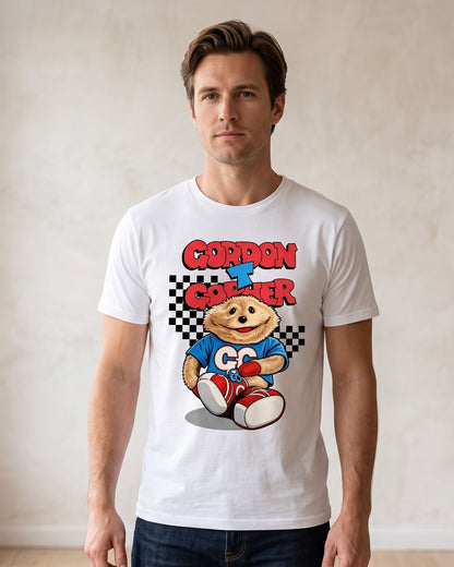 A man wearing a white short-sleeve t-shirt with a colorful retro graphic of the iconic TV broom cupboard character and the text 'Gordon T Gopher' in red and blue, standing in a brightly lit room with a textured beige wall.