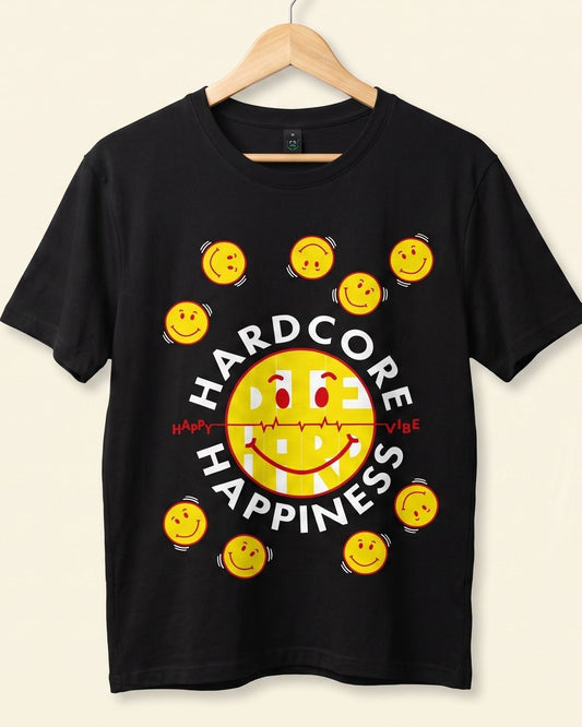 A black short-sleeve t-shirt hanging on a wooden hanger against a light beige background. The shirt features a graphic design with the words 'HARD CORE HAPPINESS' in white, surrounding a large yellow smiley face and smaller yellow smiley faces arranged around it.