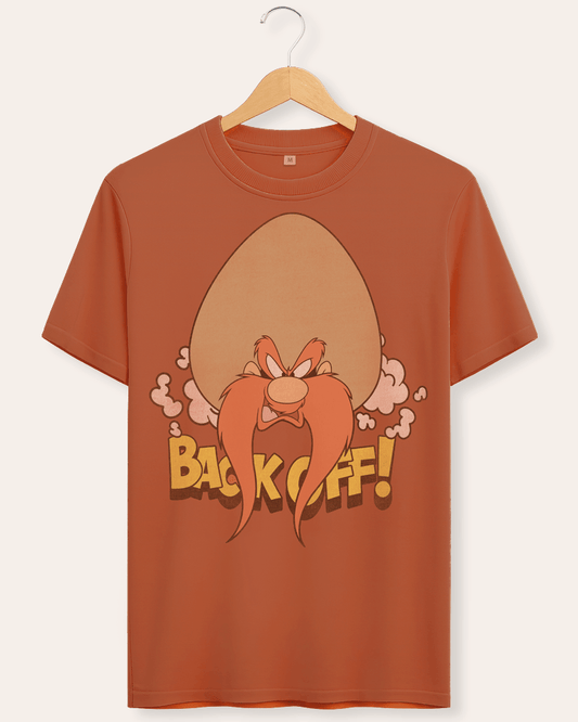 A rust-brown crewneck t-shirt hanging on a wooden hanger against a light beige background. The shirt features a graphic of the cartoon character Yosemite Sam with Back Off text in a vintage look