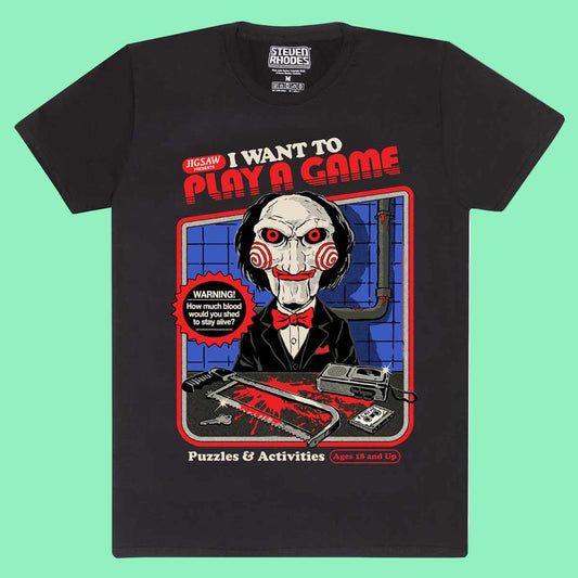 A black t-shirt with a graphic print of a character from the popular SAW horror franchise, along with text that reads 'I WANT TO PLAY A GAME' and 'Puzzles & Activities'. 