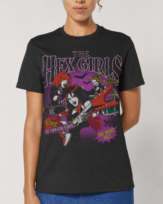 A woman wearing a black graphic t-shirt featuring the band 'The Hex Girls' with stylized illustrations in purple and red tones, against a plain light grey background.
