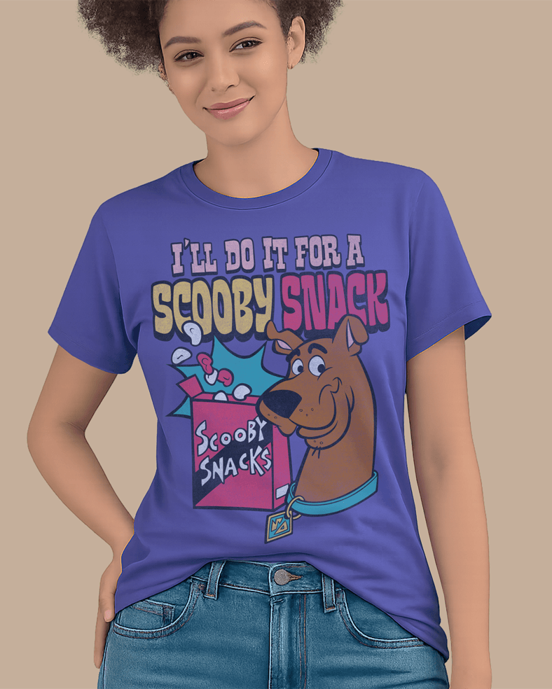 A woman wearing a dusk blue Scooby-Doo graphic t-shirt with the text 'I'LL DO IT FOR A SCOOPY SNACK' and an illustration of Scooby and a snack box, paired with blue jeans against a solid beige background.