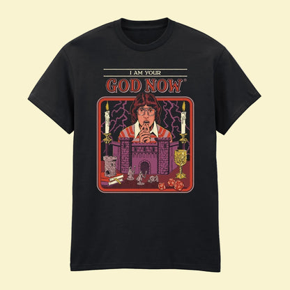 A black short-sleeve crewneck t-shirt featuring a colorful graphic print on the front. The graphic shows a man with glasses in front of a Dungeons and Dragons castle setting, with candles, lightning, and the text 'I AM YOUR GOD NOW' above.