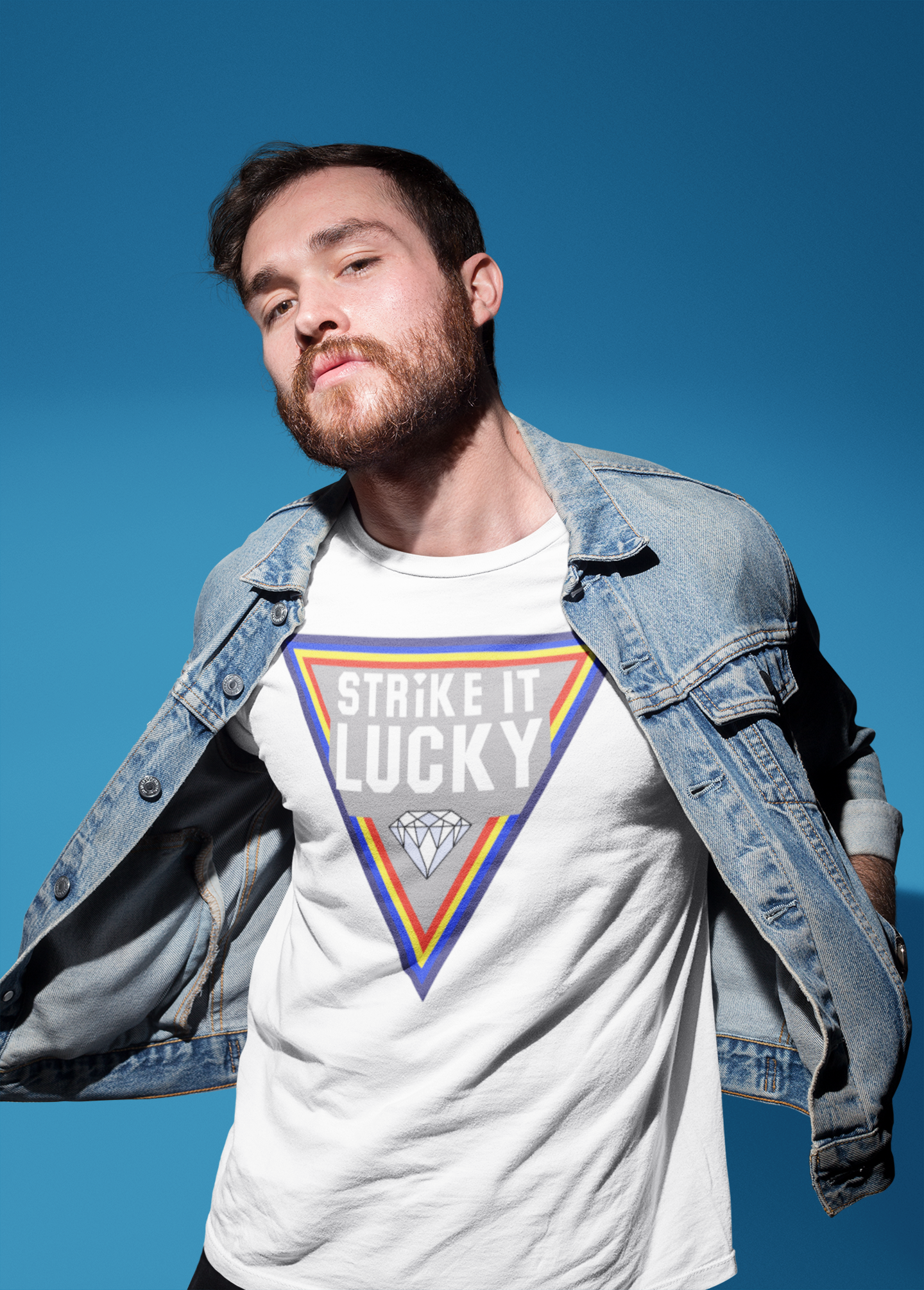 Man wearing a white t-shirt with a colourful Strike it Lucky graphic and text against a blue sky