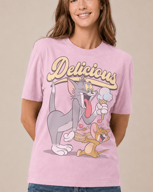 A woman wearing a light pink graphic t-shirt featuring Tom and Jerry characters eating ice cream with the word 'Delicious' printed above them, set against a solid beige background.