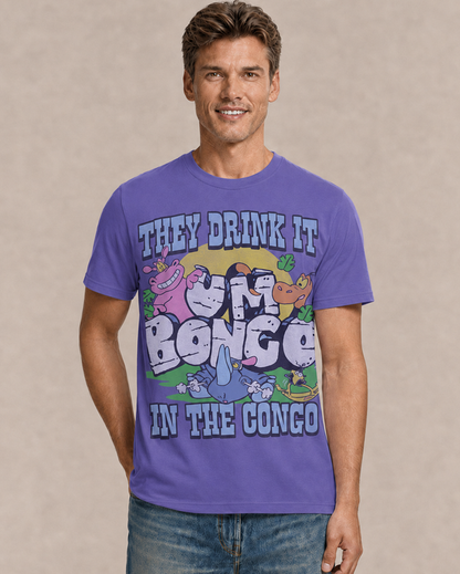 A man wearing a purple graphic t-shirt with cartoon characters and the text 'THEY DRINK IT IN THE CONGO', paired with blue jeans, against a neutral beige background.