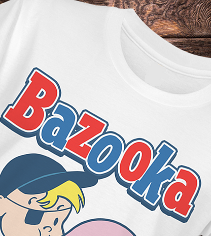 White t-shirt with 'Bazooka' graphic design on a wooden surface