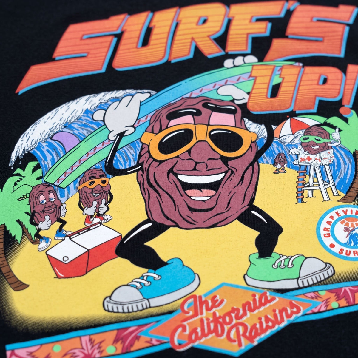 Close-up of California Raisins Surf’s Up retro graphic on black T-shirt