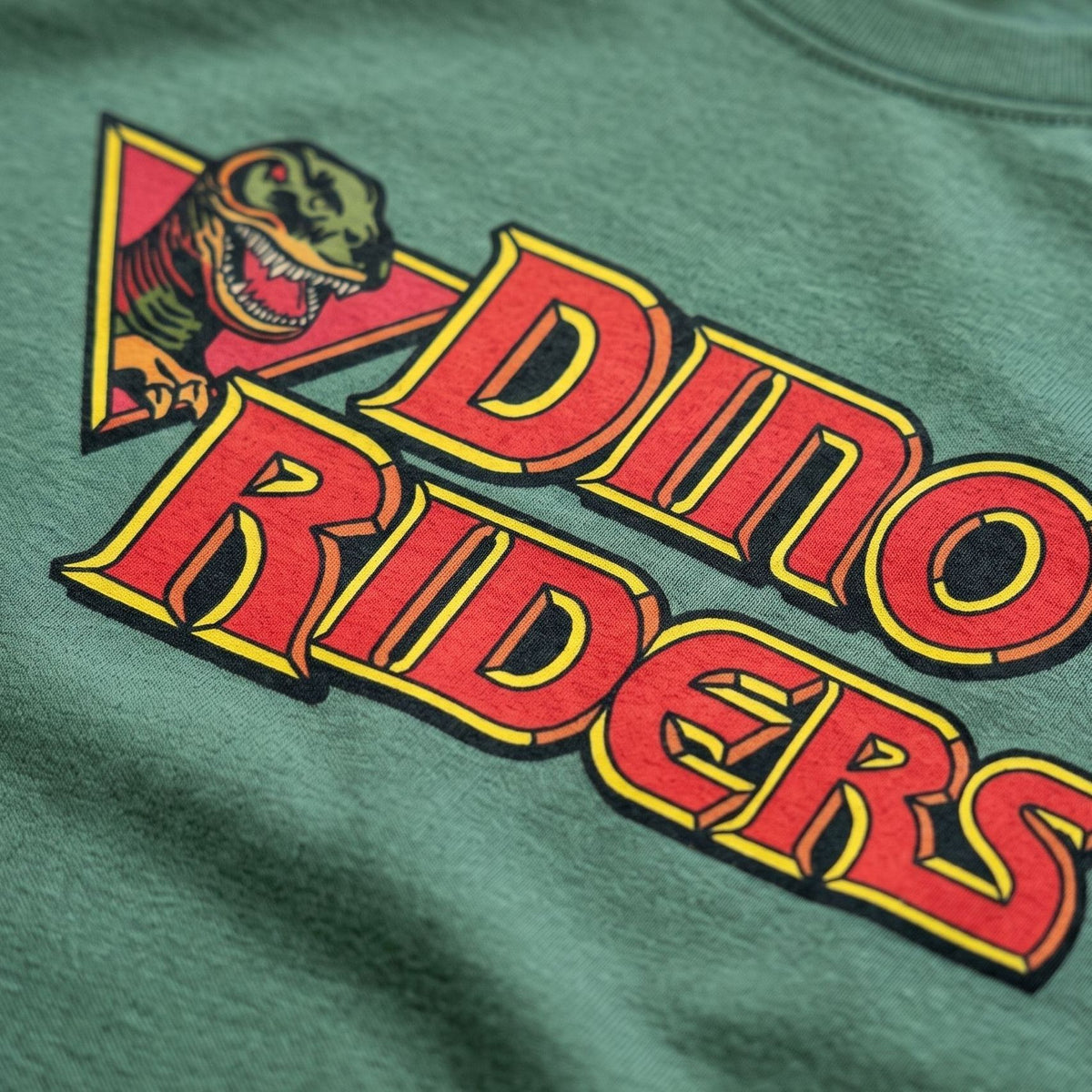 Close-up of colourful Dino Riders retro dinosaur logo T-shirt graphic