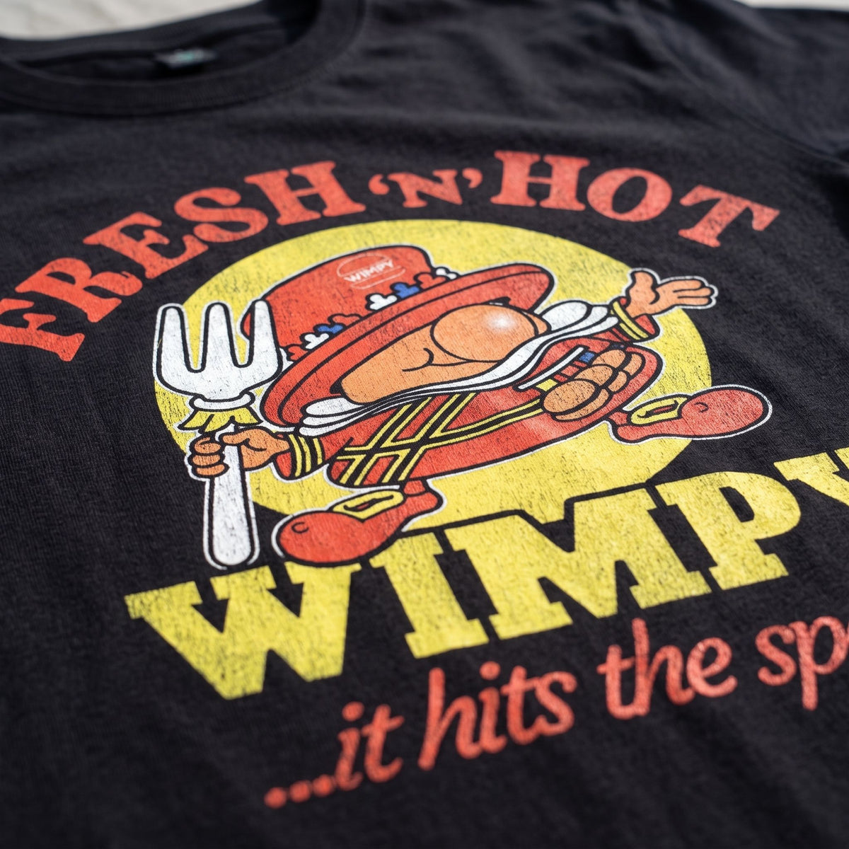 Close-up of Fresh n Hot Wimpy retro graphic printed on black T-shirt