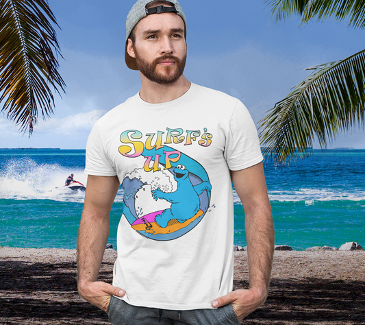 Man wearing Official Sesame Street T-shirt by Famous Forever. Unisex short sleeve crew neck white t-shirt featuring retro 80s style Cookie Monster riding a wave on his cookies surf board design with Surfs Up text above